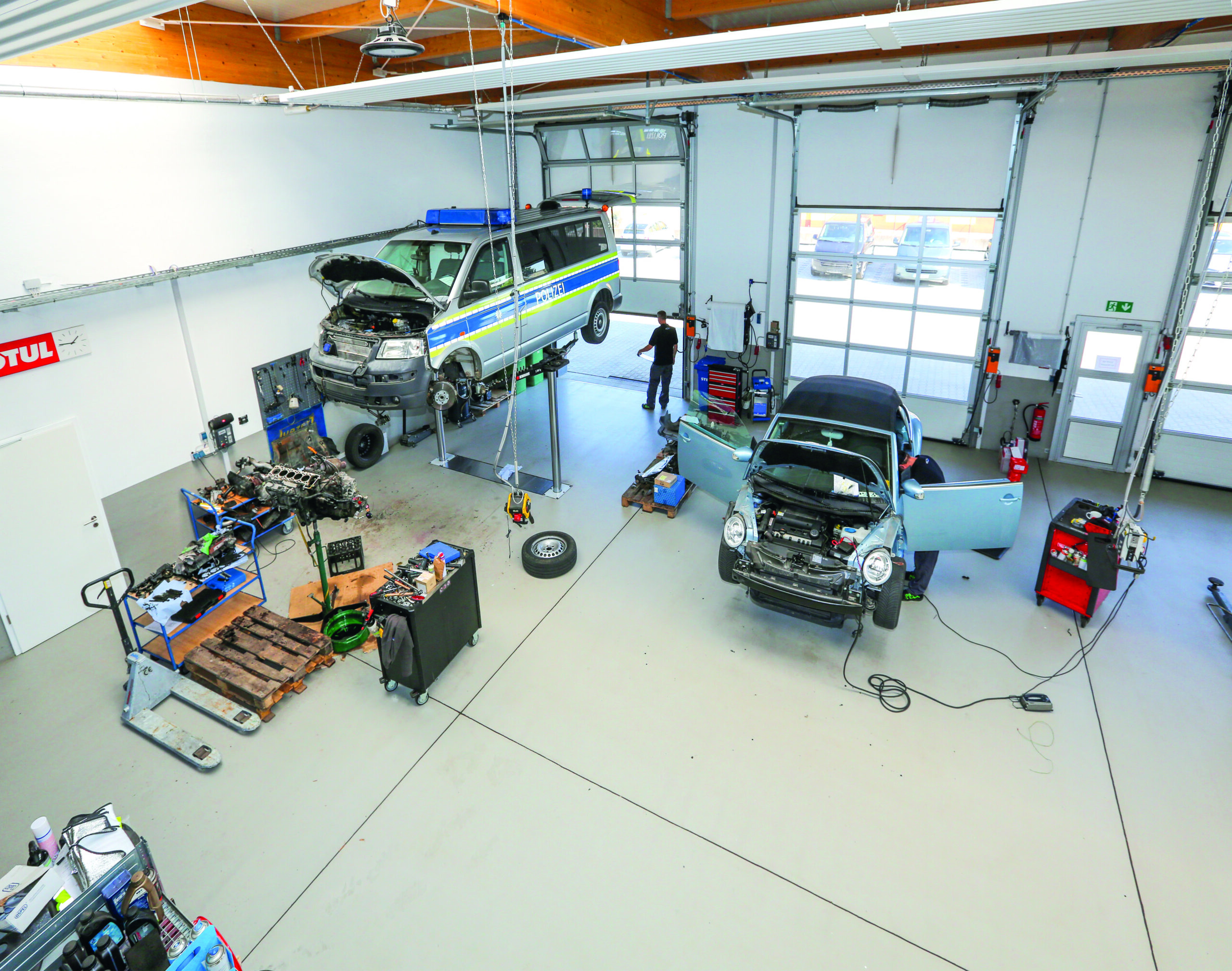 Innenansicht der modernen KFZ-Werkstatt von KFZ-Technik Schmitt in Oberhaid mit Hebebühnen, Fahrzeugen und professioneller Ausstattung.